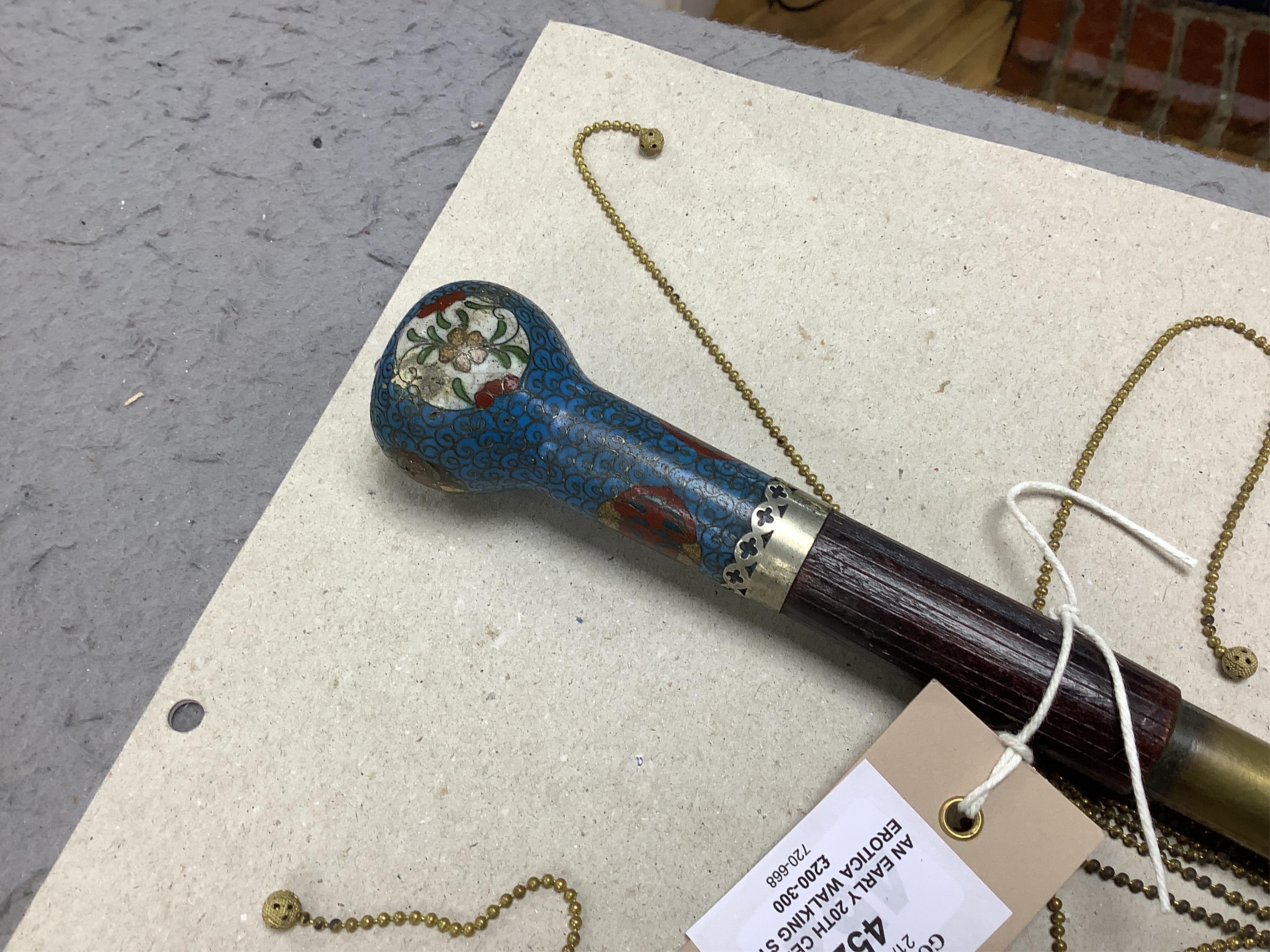 An early 20th century erotica walking stick with cloisonné enamel handle and concealed chain flogger, 86cm long. Condition - good.